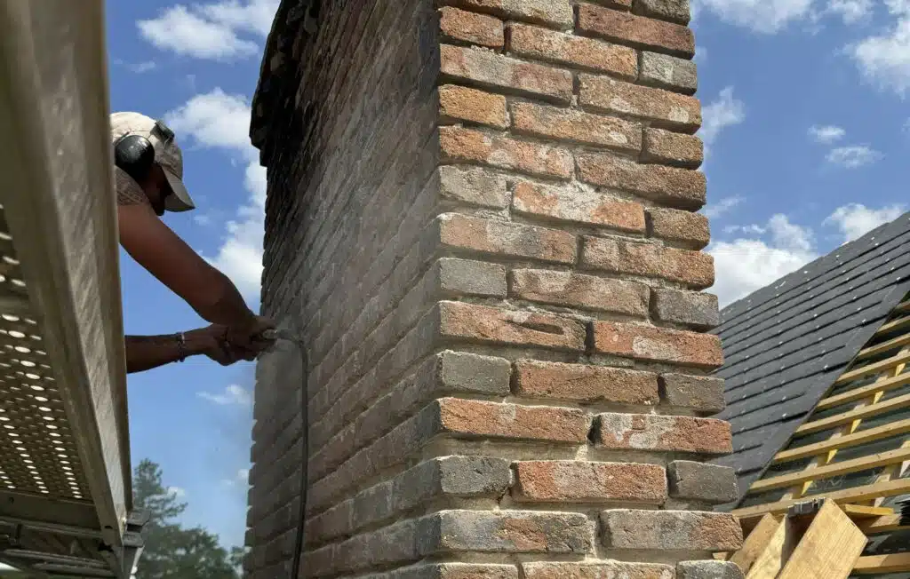Reprise des joints d’une cheminée en briques sur une toiture de château en Sologne
